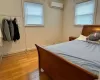 Bedroom featuring light wood finished floors, multiple windows, a wall unit AC, and baseboards