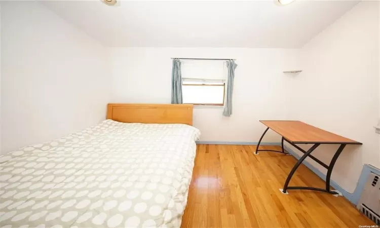 Bedroom featuring wood finished floors and radiator