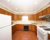 Kitchen featuring white appliances, under cabinet range hood, light countertops, and a sink