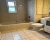 Bathroom with tile patterned flooring, toilet, vanity, tile walls, and shower / bathing tub combination