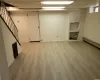 Finished basement with light wood finished floors, a paneled ceiling, visible vents, baseboards, and stairs