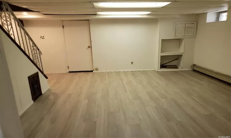 Finished basement with light wood finished floors, a paneled ceiling, visible vents, baseboards, and stairs