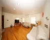 Living area featuring crown molding, recessed lighting, radiator heating unit, an AC wall unit, and light wood-type flooring