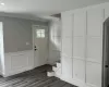 Entrance foyer with recessed lighting, a decorative wall, ornamental molding, dark wood-type flooring, and wainscoting