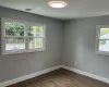 Empty room with dark wood-type flooring, visible vents, and baseboards