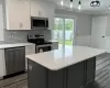 Kitchen with a wainscoted wall, wood finished floors, white cabinetry, ornamental molding, and appliances with stainless steel finishes