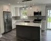 Kitchen featuring stainless steel appliances, dark wood finished floors, a sink, and light countertops