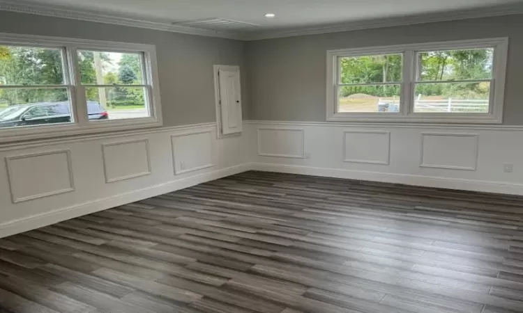 Empty room with dark wood-style floors, ornamental molding, a wainscoted wall, and recessed lighting