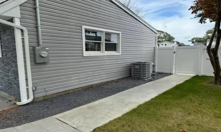 View of side of property featuring a gate, central AC, and fence