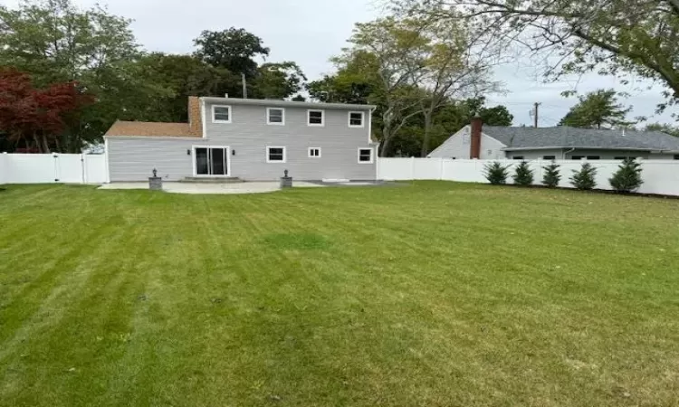 Back of house featuring a patio area, a fenced backyard, a gate, and a lawn