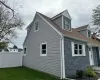 View of side of property featuring stone siding, fence, and a lawn