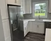 Kitchen featuring stainless steel appliances, white cabinetry, a sink, and dark wood-type flooring