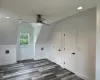 Bonus room with dark wood-style floors, lofted ceiling, visible vents, and baseboards