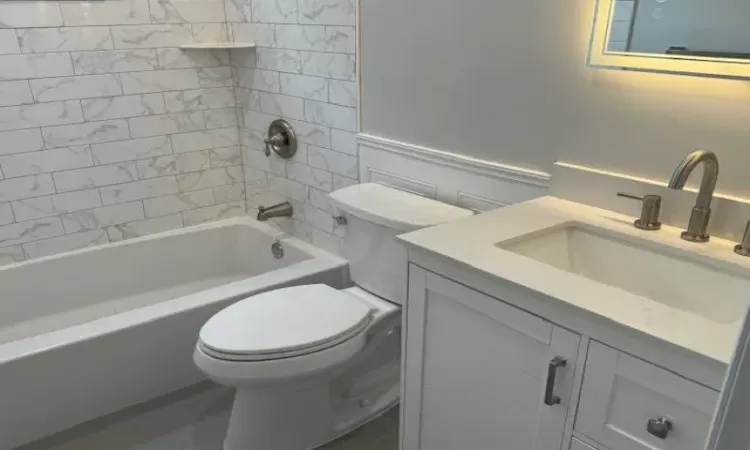 Bathroom featuring shower / bathing tub combination, vanity, and toilet