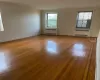 Unfurnished room with baseboards, wood-type flooring, and radiator