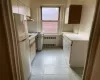 Kitchen featuring under cabinet range hood, light countertops, freestanding refrigerator, and radiator