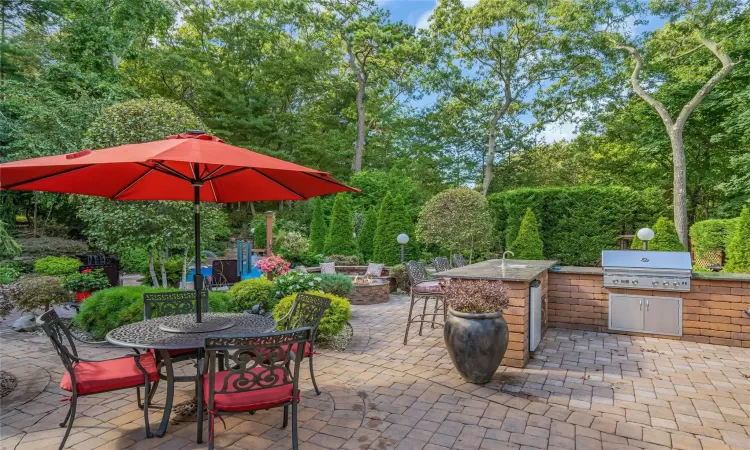 View of patio with exterior kitchen, outdoor dining area, a grill, and a fire pit