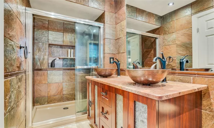 Primary Bathroom featuring a stall shower, tile walls, and a sink