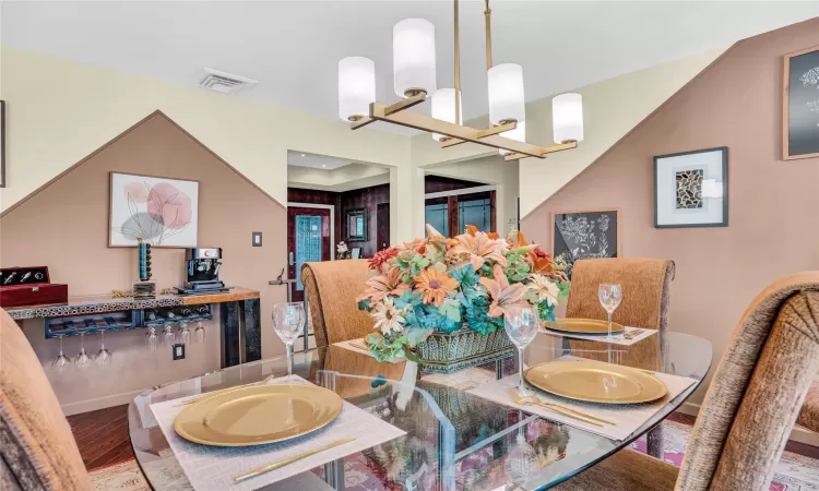 Dining space with visible vents, a notable chandelier, baseboards, and wood finished floors