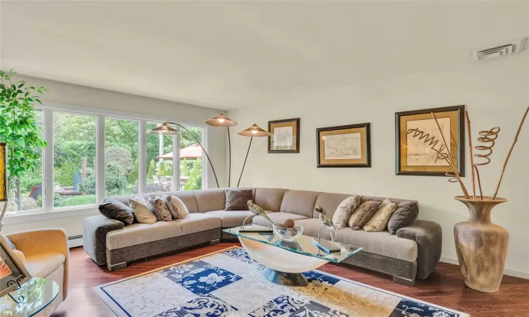 Living room with a baseboard radiator, visible vents, and wood finished floors