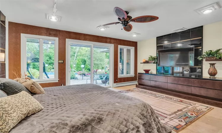 Bedroom with access to exterior, a baseboard radiator, visible vents, and a ceiling fan