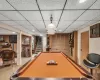 Pool Table in basement with a paneled ceiling. Door leads to organized toll room.