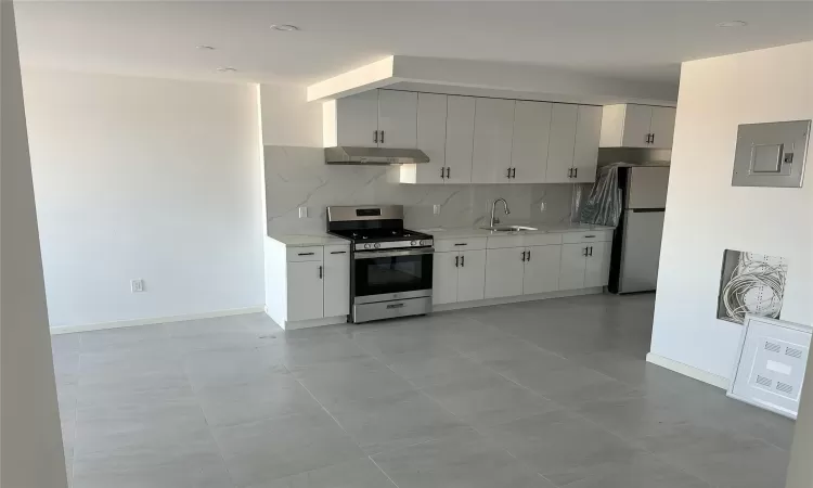 Kitchen with a sink, electric panel, under cabinet range hood, stainless steel appliances, and decorative backsplash