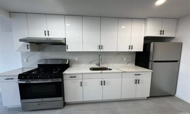 Kitchen featuring appliances with stainless steel finishes, a sink, white cabinets, and under cabinet range hood