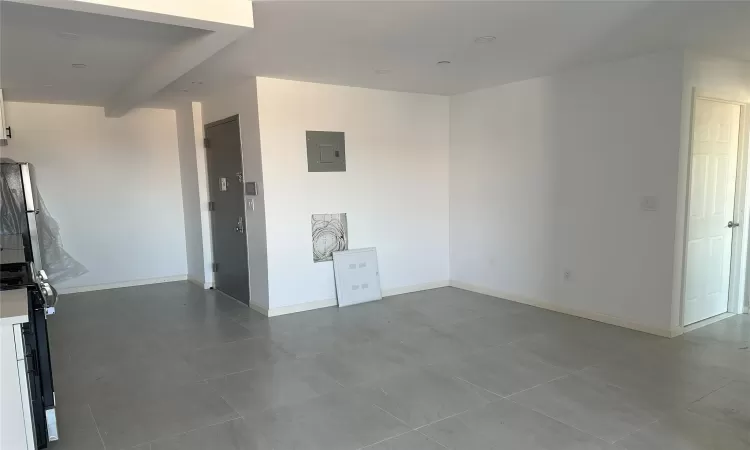 Empty room featuring electric panel and baseboards