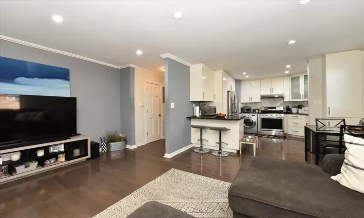 Living area featuring washer / dryer, baseboards, dark wood-style floors, crown molding, and recessed lighting