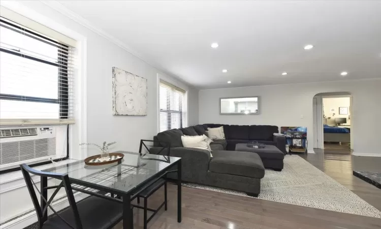 Living room featuring arched walkways, crown molding, recessed lighting, and wood finished floors