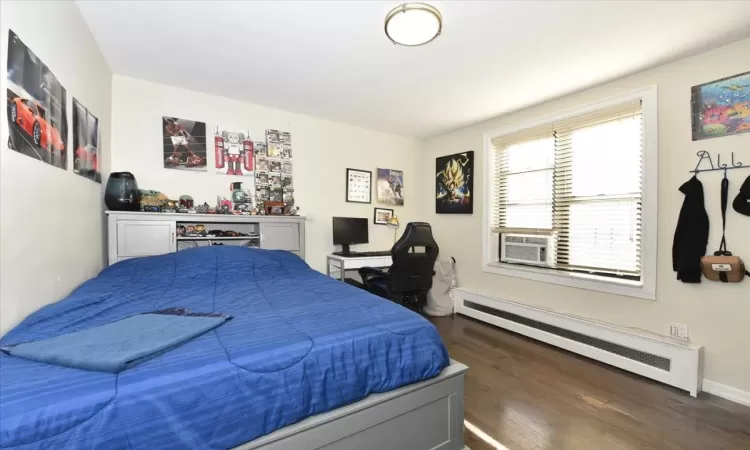 Bedroom featuring cooling unit, dark wood finished floors, and baseboard heating