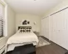 Bedroom with a baseboard heating unit, dark wood-type flooring, two closets, and baseboards