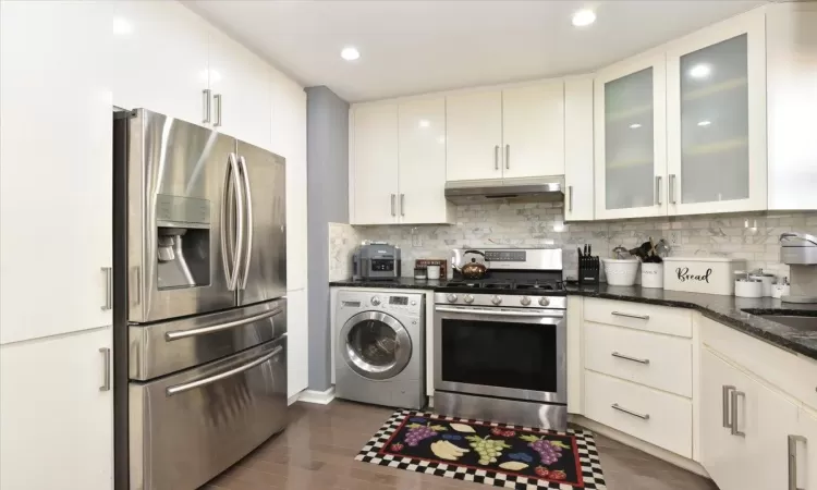 Kitchen with under cabinet range hood, tasteful backsplash, washer / clothes dryer, and stainless steel appliances