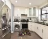 Kitchen with under cabinet range hood, stainless steel appliances, a sink, decorative backsplash, and washer / dryer