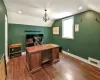 Home office with lofted ceiling, visible vents, dark wood finished floors, and baseboards