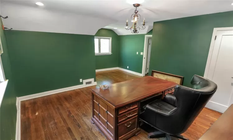 Bedroom used as an office with baseboards, visible vents, wood finished floors, vaulted ceiling, and a chandelier