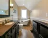 Full bath on the second floor featuring lofted ceiling, toilet, vanity, wood finished floors, and a freestanding tub