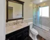 Full bath with  finished floors, vanity, toilet, and bath / shower combo with glass door