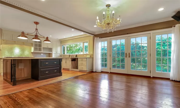 Kitchen with french doors, stainless steel dishwasher, light wood-type flooring, and decorative backsplash