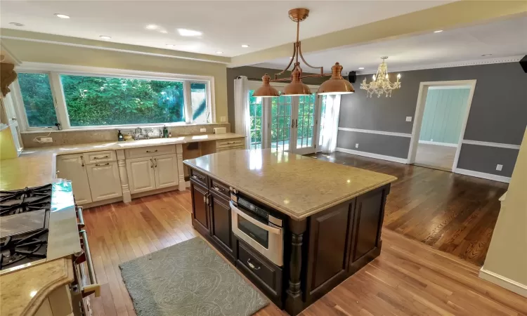 Kitchen featuring light stone counters, light wood finished floors, tasteful backsplash, a sink, and baseboards