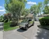 View of front facade with a front yard, a chimney, a semi attached garage, and an outbuilding