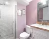 Basement bathroom featuring a stall shower, vanity, and toilet