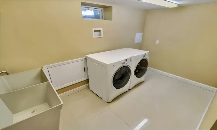 Laundry area in the basement featuring laundry area, baseboards, washing machine and clothes dryer, and light tile patterned floors