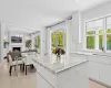 Kitchen with a lit fireplace, a kitchen island, light wood-style flooring, and white cabinets