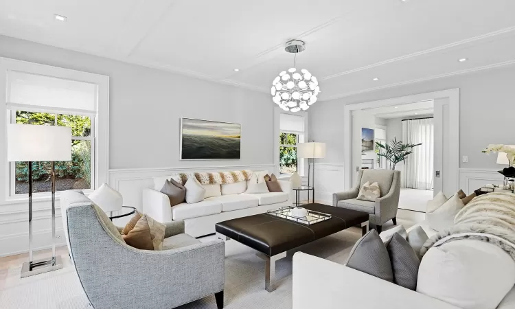 Living area with a wainscoted wall, a chandelier, a decorative wall, and beamed ceiling