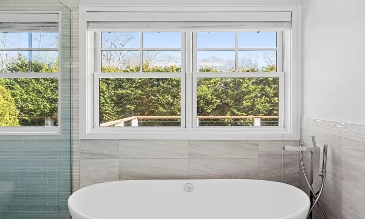 Full bathroom with a freestanding tub, tile walls, and a wealth of natural light