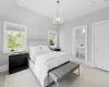 Bedroom with light wood-style floors, a chandelier, connected bathroom, and baseboards