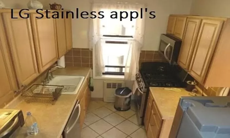 Kitchen with light tile patterned floors, visible vents, appliances with stainless steel finishes, light countertops, and a sink