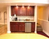 Kitchen with reddish brown cabinets, tasteful backsplash, refrigerator, light wood-type flooring, and a sink